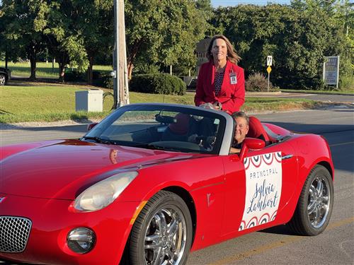 Principal Sylvia Lambert on back of convertible